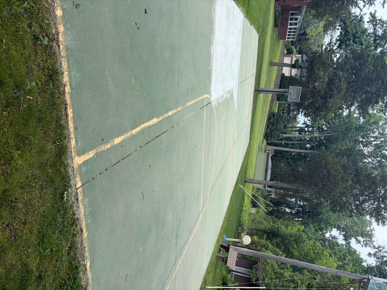 Backyard sport court half cleaned showing the difference pressure washing makes